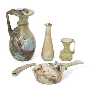 Four Roman glass vessels, circa 2nd-4th Century A.D.
		
		Including a small pale green glass skillet, 13.8cm long, 7.2cm diam of bowl; a green glass jug with