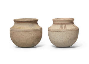 Two Iranian small buff pottery vessels with carinated shoulder and everted rim, the shoulder similarly decorated on both with two groups of parallel stripes on